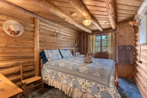 Cozy log cabin bed with a cute stuffed animal sitting on top.