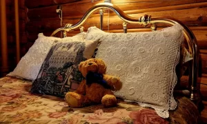 A teddy bear sitting on a bed with pillows, creating a cozy and comforting scene.